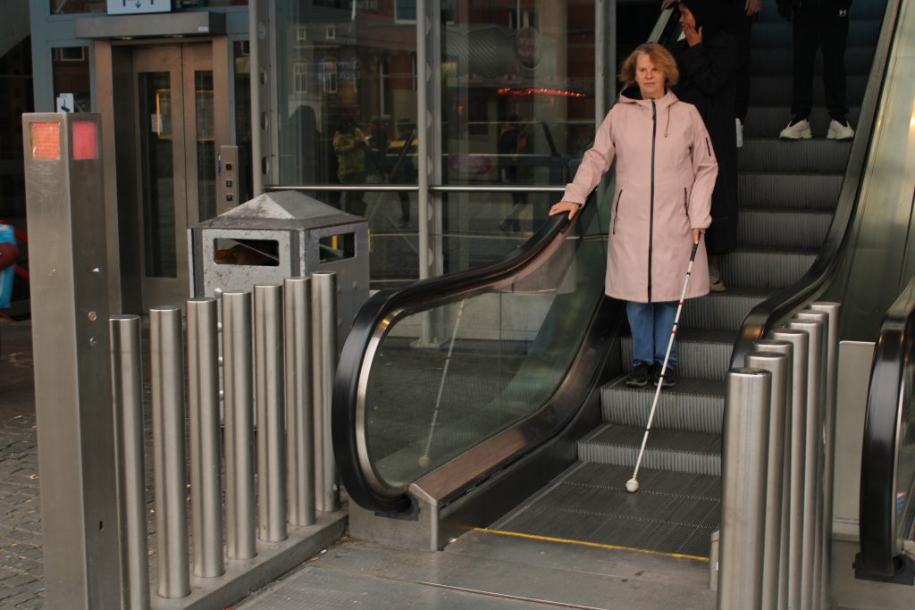 Inge met stok van roltrap